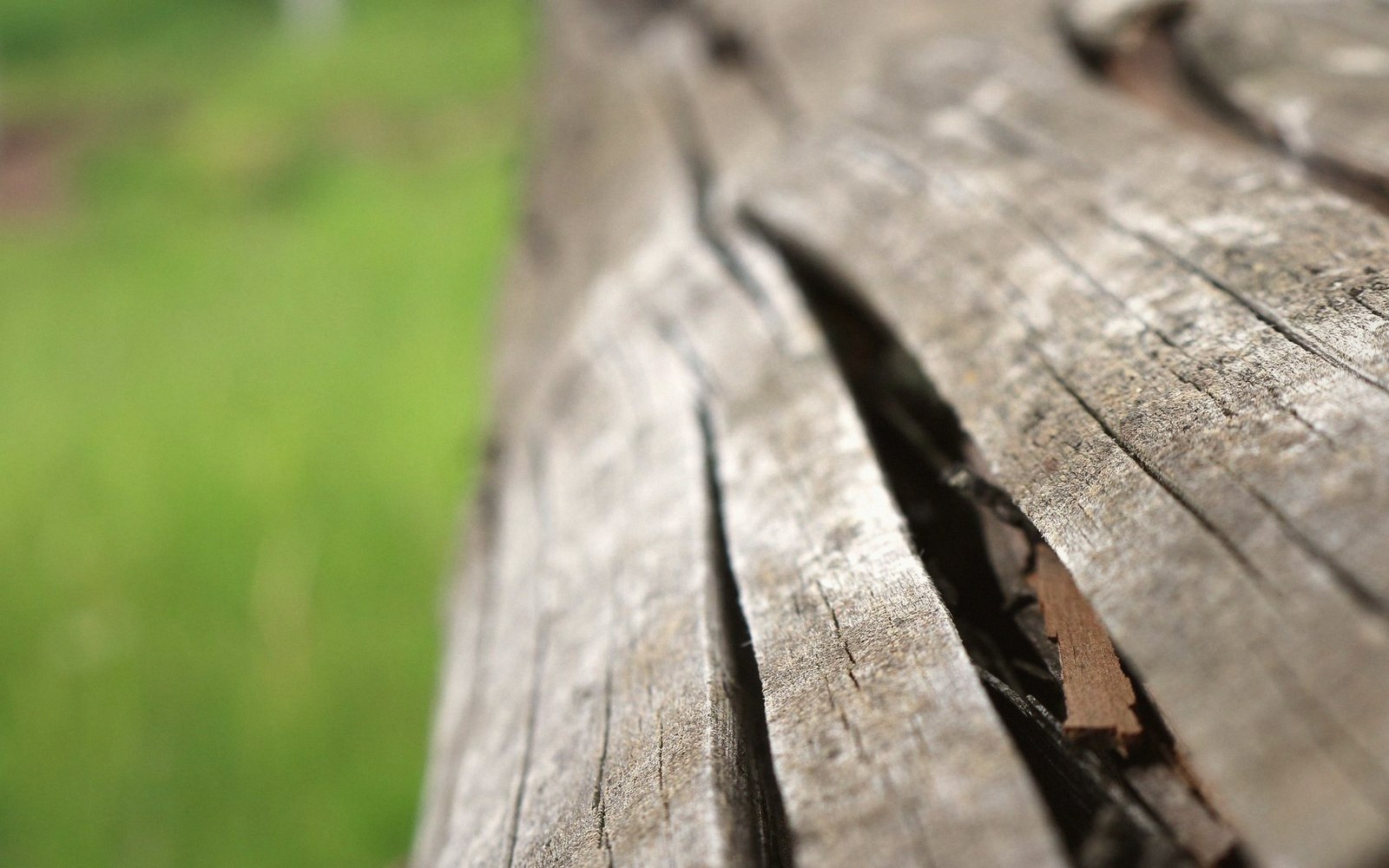 Close-up of a weathered wooden beam with a deep crack running along its grain